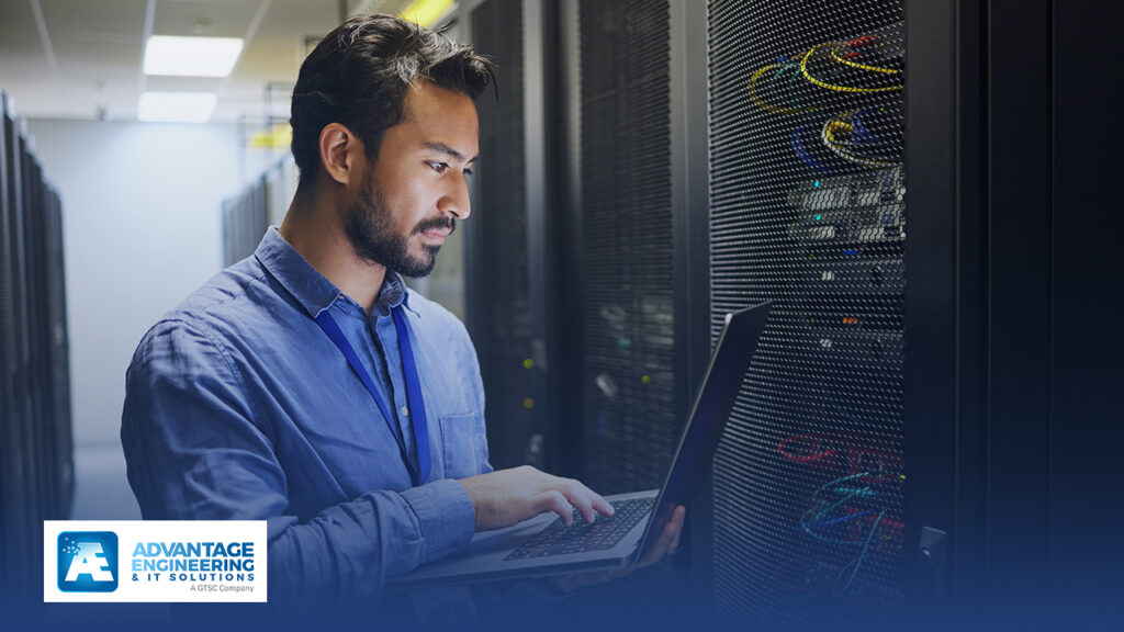 Man working on laptop in server room.