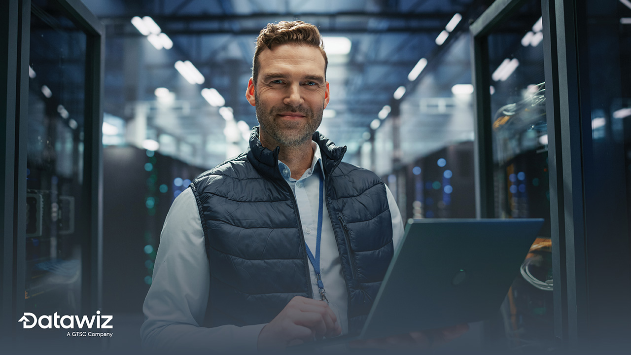 Professional in data center holding laptop looking confident